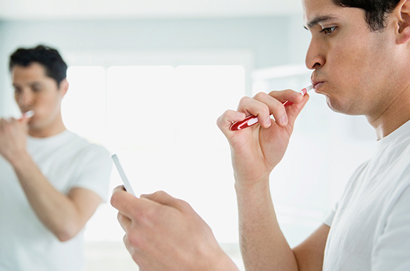 Man Brushing Teeth Smartphone Treat Gum Disease parodontax Man Brushing Teeth Smartphone Treat Gum Disease parodontax